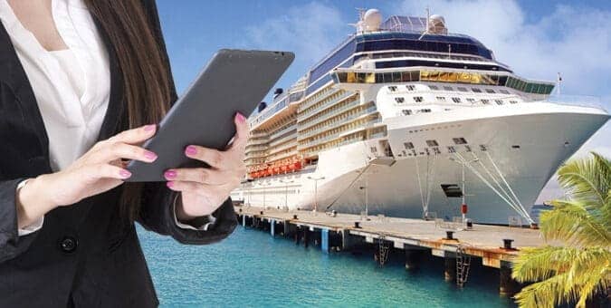 Mujer usando una tablet con un crucero en una marina en el fondo: Mejorando Operaciones de Hospitalidad y Experiencia del Huésped a través de la Integración del PMS